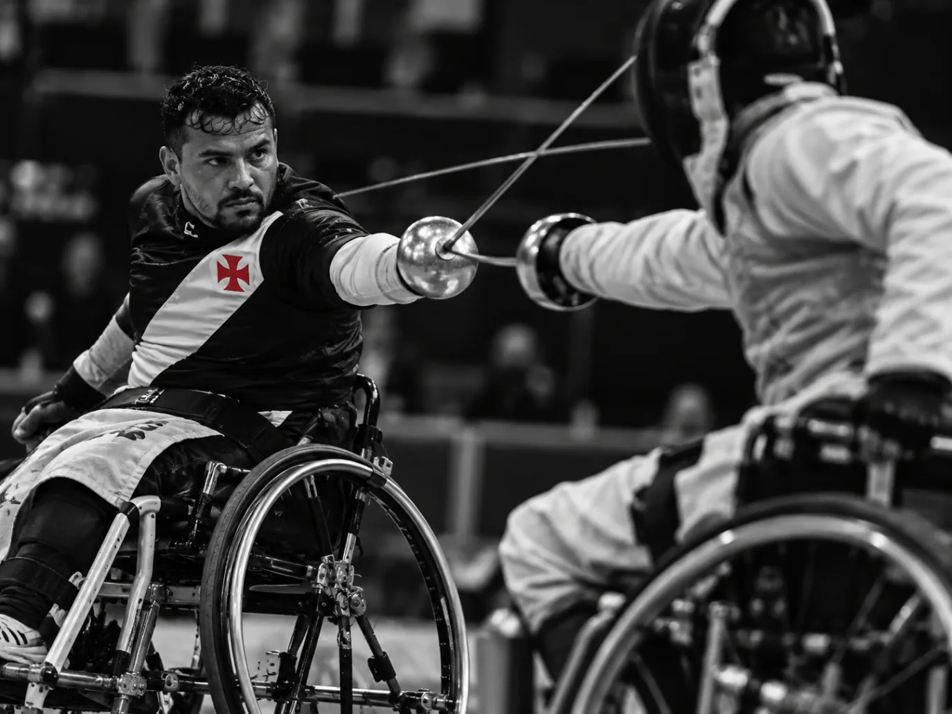 Dois atletas em cadeiras de rodas disputando um toque de esgrima